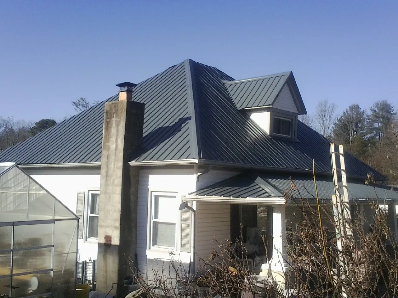 Dark blue standing seam metal roof on a white farmhouse with dormer — Slate & Tile Roof Repair by Roofing Brothers in Pennington